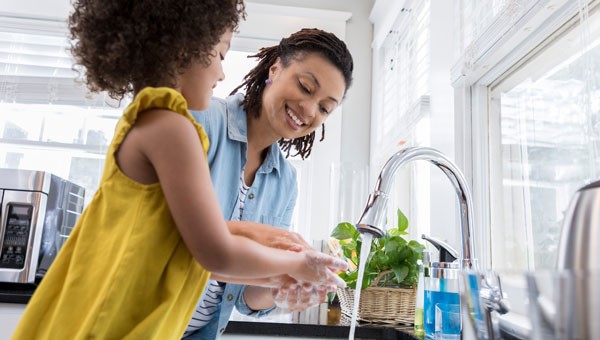 Mother and Daughter in Kitchen Washing Hands